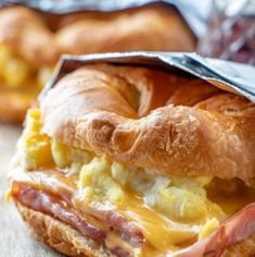 a close up of a bagel sandwich with eggs and ham in it on a table