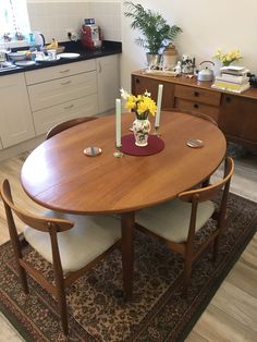 a wooden table with chairs around it and flowers on the table in front of it