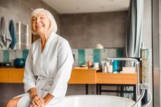 an older woman sitting on the edge of a bathtub