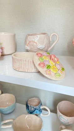 there are many cups and bowls on the shelf