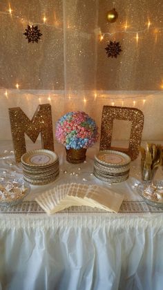 a table topped with plates and vases filled with flowers next to the letter m