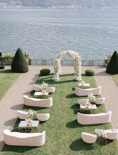 an outdoor ceremony setup with white flowers and greenery on the lawn by the water