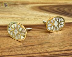 two gold and white cufflinks on a wooden surface