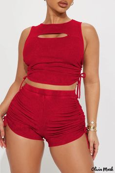 a woman wearing red shorts and a cropped top with cutouts on the sides