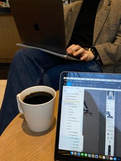 a man sitting in front of a laptop computer next to a cup of coffee