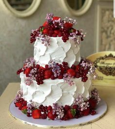 a three tiered cake with berries and flowers on it