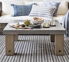 a coffee table with food on it in front of a white couch and striped rug