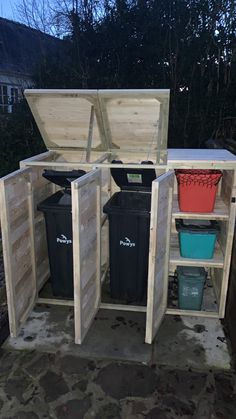 an outdoor storage shed with several bins and trash cans