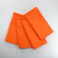 four orange napkins folded on top of each other