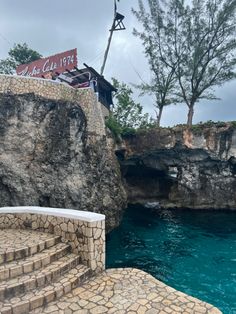 stairs lead down to the blue water in front of a cliff with a sign on it