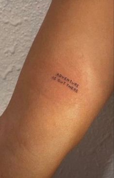 a person with a small tattoo on their arm that says, adventure is out there