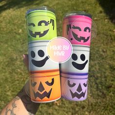 three cups with faces painted on them are held in the air by someone's hand