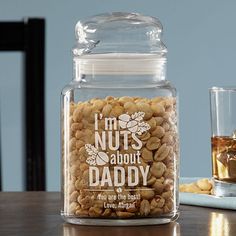 a glass jar filled with nuts sitting on top of a table next to two glasses