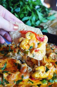 a person is dipping some food into a pan filled with shrimp and tortilla