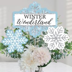 a vase filled with flowers sitting on top of a white table covered in snowflakes