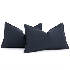 two dark blue pillows sitting side by side on top of each other in front of a white background