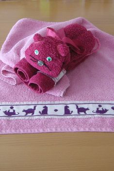 a pink towel with a teddy bear on it sitting on top of a wooden table