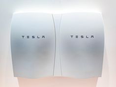 two white wall mounted mirrors with the word tesla on them in front of each other