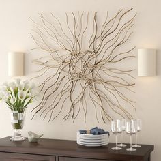 a dining room table with plates and glasses on it, next to a wall sculpture