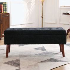 a black bench sitting on top of a rug in front of a table and chair