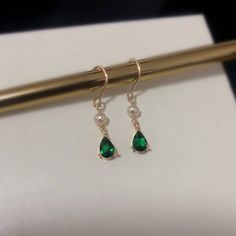 Introducing our stunning minimalist teardrop emerald gold and pearl drop earrings! Handcrafted with care and attention to detail, these earrings are the perfect blend of classic and modern style. The teardrop-shaped emerald gemstones are delicately set in 18k gold plated, giving these earrings an elegant and timeless look. The addition of the lustrous cultured pearls adds a touch of sophistication to these already stunning earrings. Measuring approximately 31mm in length, 5mm width, these earrin Green Teardrop Pearl Earrings For Wedding, Elegant Teardrop Earrings For May Birthstone Gift, Classic Green Pearl Drop Earrings, Green Elegant Pearl Drop Earrings, Elegant Green Drop Pearl Earrings, Elegant Green Teardrop Pendant Earrings, Elegant Green Pearl Drop Earrings, Elegant Dangle Pearl Earrings For May Birthstone, Elegant Teardrop Earrings For May Birthstone