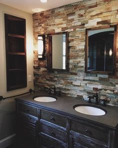 a bathroom with two sinks and a stone wall