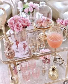 a gold tray with pink flowers and champagne glasses on it is sitting in front of a white couch