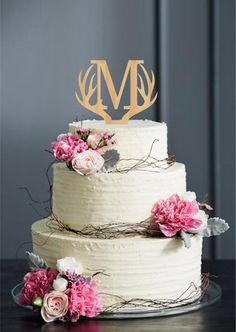 a three tiered cake with flowers on top and the word love spelled in gold