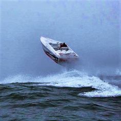 a speed boat is in the air as it speeds through the water on a cloudy day