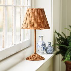 a wicker lamp sitting on top of a window sill next to a potted plant