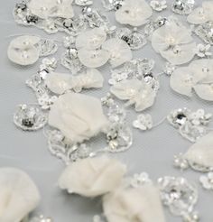 white flowers and crystal stones are scattered on a tablecloth with silver sequins