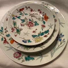 three plates are stacked on top of each other with flowers and butterflies painted on them