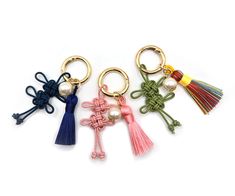 three key chains with tassels and cross charms on each one, all in different colors