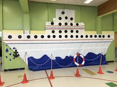 a large white boat sitting in a room next to some orange traffic cones and poles