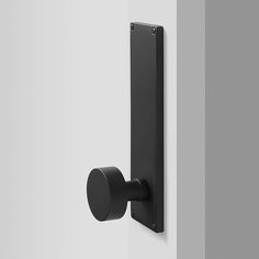 a black door handle on the side of a white wall with a round knob attached to it