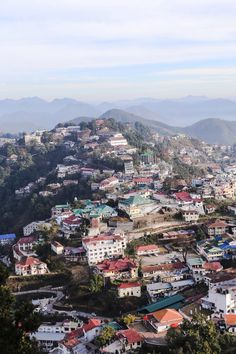 a city with lots of houses and mountains in the background