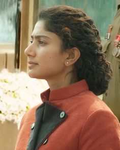 a woman in an orange jacket is looking off to the side with other uniformed people behind her