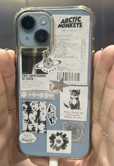 someone is holding up their phone case with stickers on it and there are other things in the back