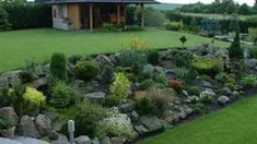 a garden with rocks and plants in front of a house that has a gazebo on it