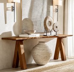 a table with two vases on it in front of a mirror and lamp shade