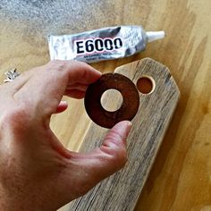 a person holding an object in their hand near a piece of wood and a tube of toothpaste