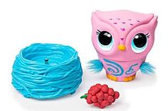 a pink owl toy next to a spool of blue yarn and a red berry