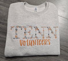 a gray shirt with orange letters on it