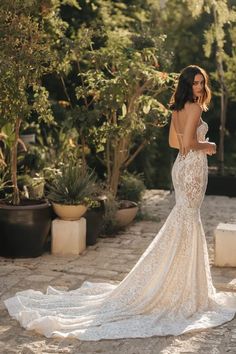 a woman in a wedding dress standing on a stone path with her back to the camera