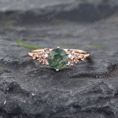 a close up view of a green stone ring on top of a rock with grass and rocks in the background