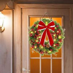 a christmas wreath hanging on the front door with lights and decorations attached to it's side