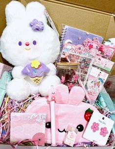 a white teddy bear sitting on top of a box filled with items