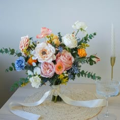 a bouquet of flowers sitting on top of a table next to a wine glass and candle