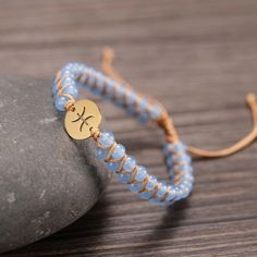 a blue beaded bracelet with a gold disc on it and a rope wrapped around the clasp