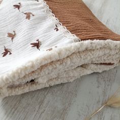 a brown and white blanket laying on top of a wooden floor next to a feather